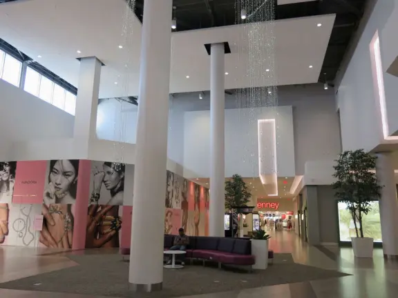 A modern, elegant mall with a Miniso Asian goods store, Hollister Co. teen clothing, Claire's Accessories, Hobby Lobby crafts, The Children's Place kids clothing, and large department stores.