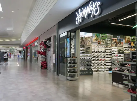 A modern, elegant mall with a Miniso Asian goods store, Hollister Co. teen clothing, Claire's Accessories, Hobby Lobby crafts, The Children's Place kids clothing, and large department stores.