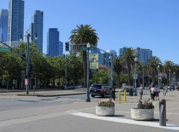 Modern area, also called Mission Bay, with French bakery, waterfront bike path that connects to Embarcadero, and views across to Oracle Park stadium and the Bay Bridge.