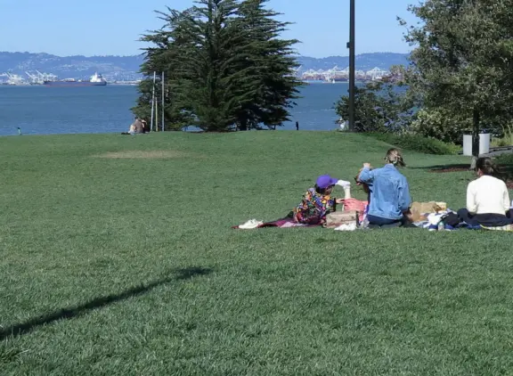 Modern area, also called Mission Bay, with French bakery, waterfront bike path that connects to Embarcadero, and views across to Oracle Park stadium and the Bay Bridge.