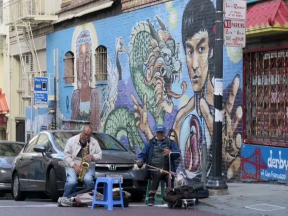 Street with red lanterns with gold tassles, whimsical lampposts, and storefronts that swoop up in the corners.