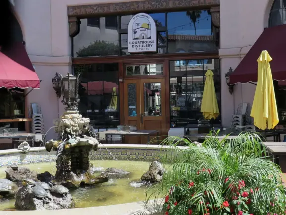 A Spanish paseo and courtyard with archways, little lights, flags, murals, lifelike statues, and fountains. At night, a magical spot!