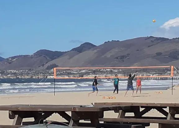 A glorious beach in Grover Beach town, with sand dunes and a wooden boardwalk, plus an octagon-shaped wooden pier in the sand.