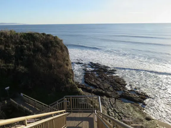 Stretch of grass with a paved walkway, flower beds, wonderful ocean views to Avila Beach, and monterey cypress trees.