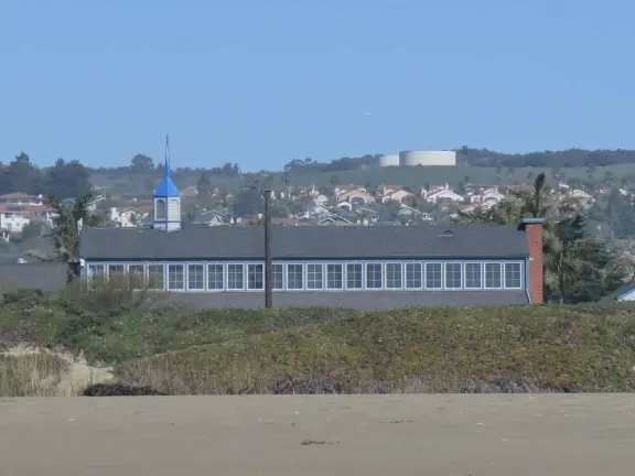 A glorious beach in Grover Beach town, with sand dunes and a wooden boardwalk, plus an octagon-shaped wooden pier in the sand.