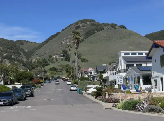 Walkway with benches above the ocean, and steps that lead down to tide pools and beach with reddish-hued sand and lovely cliffs.