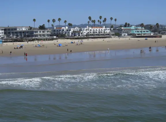 Gorgeous spot with wide pier, surfers carving the waves, whale playground, wide open attractive plaza, Pismo Beach selfie sign, and wooden promenade with views of the hills and sea.
