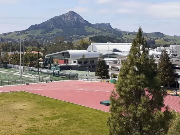 Hilly, sunny campus with tall, impressive trees and green lawns. A hands-on learning university.