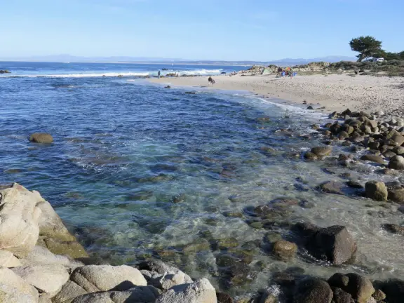 Adorable beach with jutting rocks to climb, water swooshing in, and colorful stones on the shore.