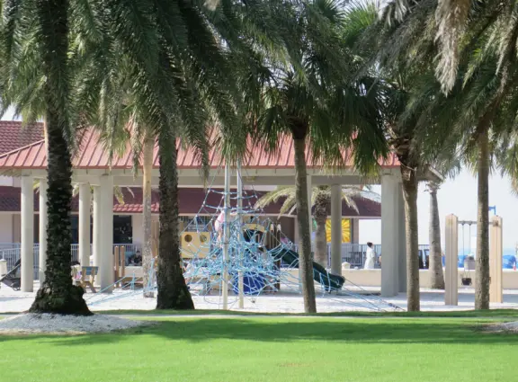 Two playgrounds (big and toddler) under huge shade canopies, on white sand, with two space nets, at the base of the gorgeous Pier 60.
