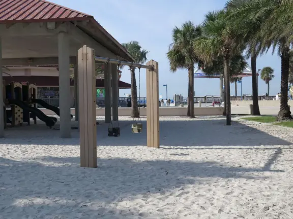 Two playgrounds (big and toddler) under huge shade canopies, on white sand, with two space nets, at the base of the gorgeous Pier 60.