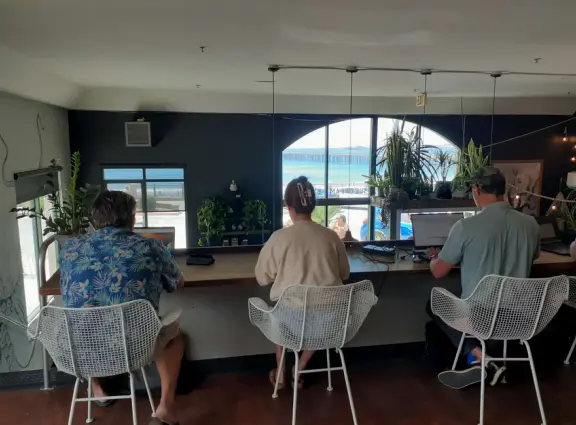People at their laptops upstairs in Kraken Coffee, with views of the pier and ocean. Too bad about the fan noise!