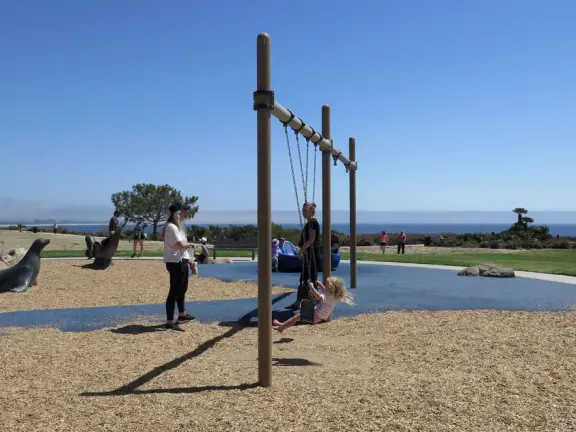 Imaginative playground with dinosaur eggs, huge green lawn, high hills in the distance, and path along the cliffs with views of the ocean and bird rocks!