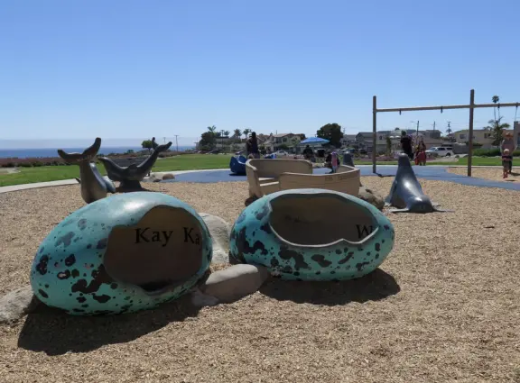 Imaginative playground with dinosaur eggs, huge green lawn, high hills in the distance, and path along the cliffs with views of the ocean and bird rocks!