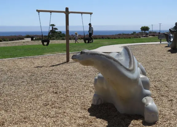 Imaginative playground with dinosaur eggs, huge green lawn, high hills in the distance, and path along the cliffs with views of the ocean and bird rocks!