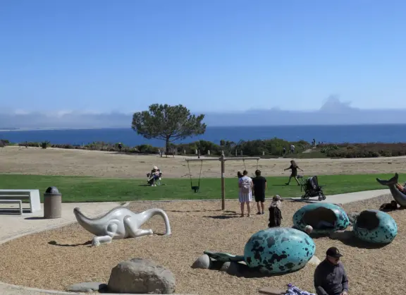 Imaginative playground with dinosaur eggs, huge green lawn, high hills in the distance, and path along the cliffs with views of the ocean and bird rocks!