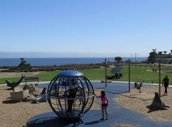 Imaginative playground with dinosaur eggs, huge green lawn, high hills in the distance, and path along the cliffs with views of the ocean and bird rocks!