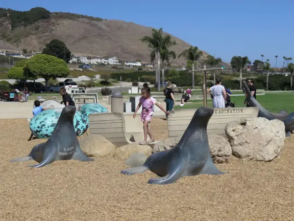 Imaginative playground with dinosaur eggs, huge green lawn, high hills in the distance, and path along the cliffs with views of the ocean and bird rocks!