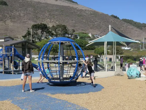 Imaginative playground with dinosaur eggs, huge green lawn, high hills in the distance, and path along the cliffs with views of the ocean and bird rocks!
