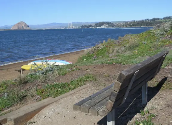 Windy estuary beach (called Baywood Park Beach), bench with views of Morro Rock, and waterfront lookout deck, plus lovely beach houses and views of the mountains.