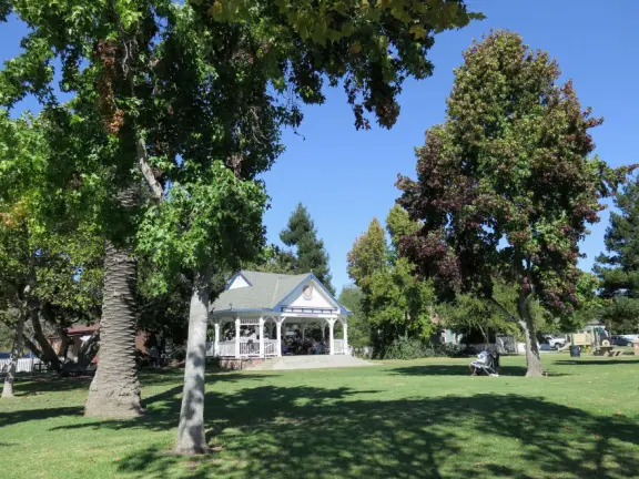 Large lush park with tall tropical trees, attractive bandstand, cute toddler playground, historic house and schoolhouse, swinging bridge to the main street, and neighborhood with cottages.