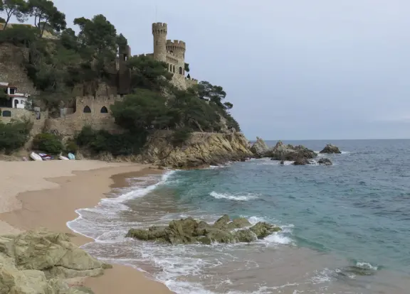 Idyllic town with cafes looking out on the ocean, castle that looks like a fairytale above the beach, and pretty square with a modernist architecture mosaic tiled church.