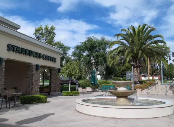 Shopping center close to the freeway, with a Barnes and Noble Bookstore and some cafes with flower planters and space outside where kids can run around.