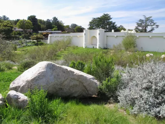 Walk in wide open spaces past boulders and flowers with views of historic Spanish-style water reservoir and mountains.