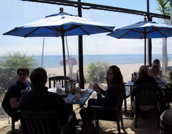 Eat at a cafe with your feet in the sand looking out at the sea in a sheltered outdoor area- magical!
