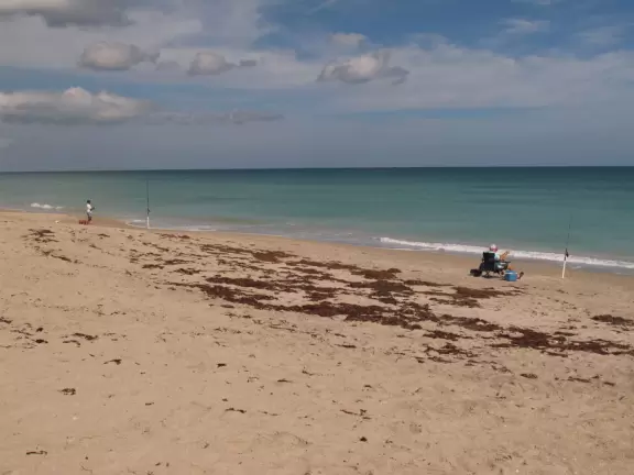 One of many beach access points leading to a shadeless beach with bright turquoise water.