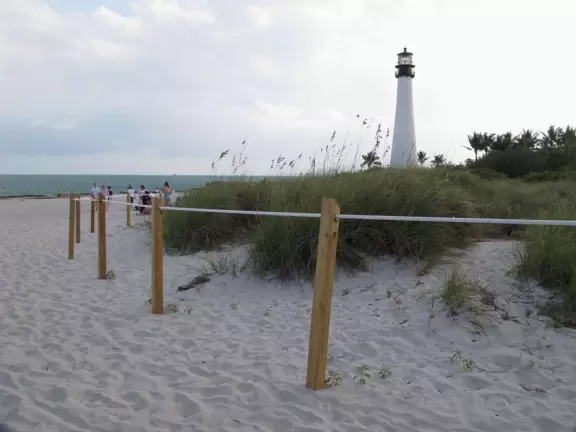 Picturesque beach with white lighthouse, happy people, and turquoise water.