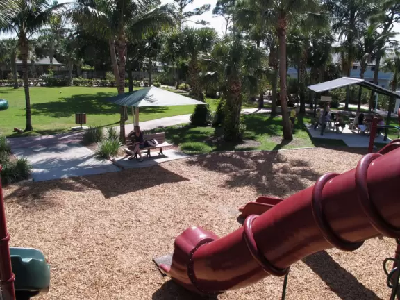 Tropical park with sky-high playground for older kids, toddler playground, fitness trail and stations, pale-lime gazebo, and spiffy basketball courts.