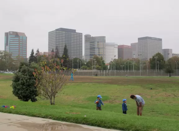 Plain-looking playground with lots of interesting climbing structures, tunnels, slides, stepping stones, bridges, swings, pretend construction trucks to drive, a giant shaded sand pit with sand funnels, all in a very urban landscape.