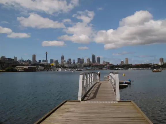 Gorgeous views of the city skyline and Anzac Bridge from a cement walking path alongside the water.