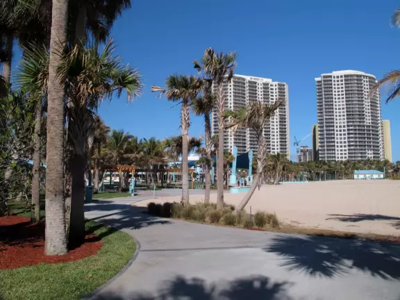 Beach with everything a beach should have: pale sand, aquamarine water, coconut palms, dunes, fit people, and cafes.