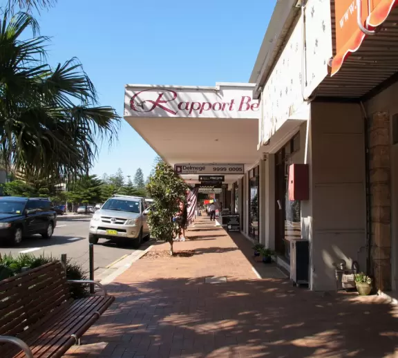 A strip of shops along the main road leading to a lovely wide beach with a playground under a forest of Norfolk pines.