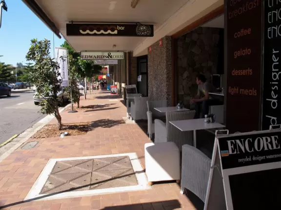 A strip of shops along the main road leading to a lovely wide beach with a playground under a forest of Norfolk pines.