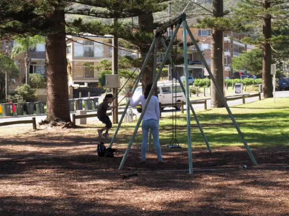 A strip of shops along the main road leading to a lovely wide beach with a playground under a forest of Norfolk pines.