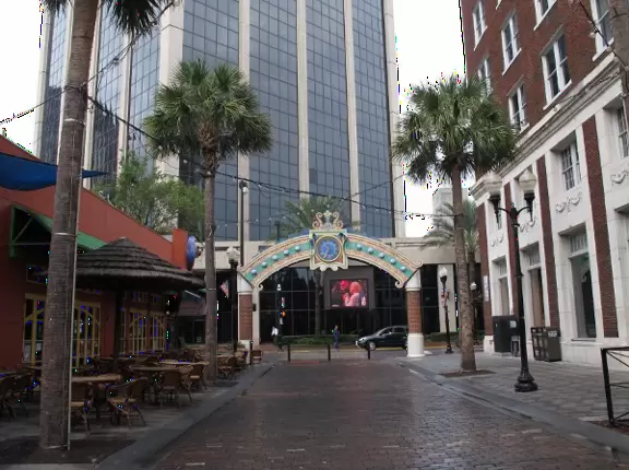 A square with fountain, grove of cypress trees, and alligator sculptures, by the main library, history center, Wall Street cafes, and Lake Eola Park.