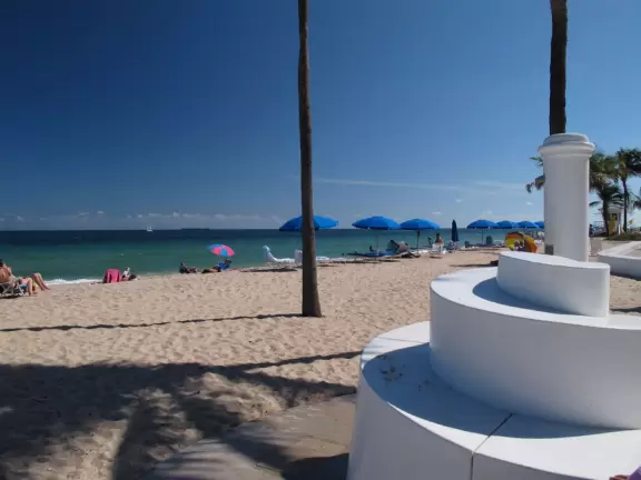 Thin strip of beach with shadeless boardwalk, white swirly wave wall, nice sand, unattractive people, and had-better-days condos.
