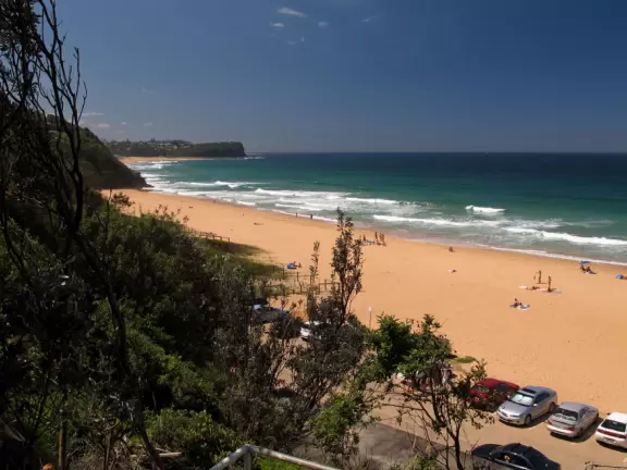 Stunning beach with orange-pink sand, blue-green water, gorgeous flower-studded headland, and rock pools that kids love to explore.