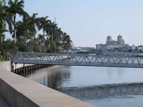 Wide walking path along the water with tropical flowers, piers, grand high rises, and palm trees- no shade though.