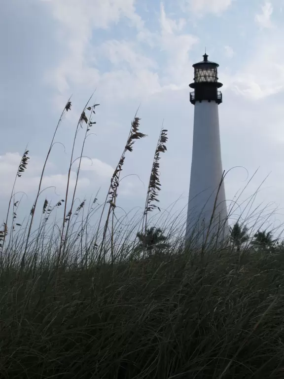 Picturesque beach with white lighthouse, happy people, and turquoise water.