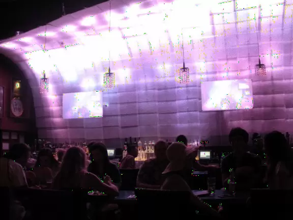 Awesome huge venue with wonderful breeze blowing through balcony, wood floors, guitars on high ceiling, and pink wave wall.