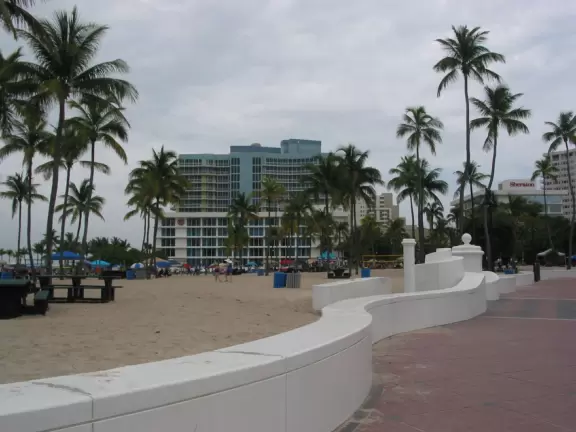 Thin strip of beach with shadeless boardwalk, white swirly wave wall, nice sand, unattractive people, and had-better-days condos.