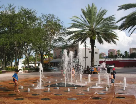Wide walking path along the water with tropical flowers, piers, grand high rises, and palm trees- no shade though.